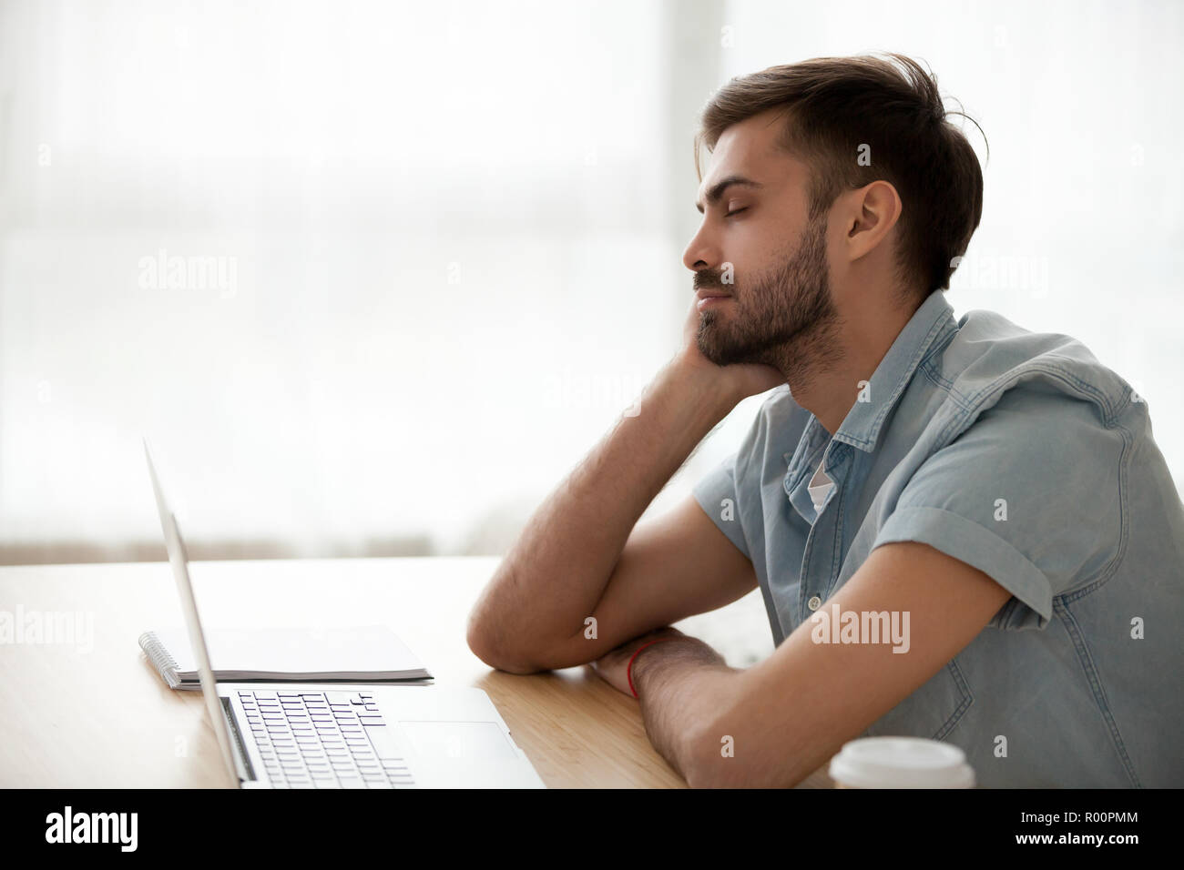 Vista lateral el hombre sentado al escritorio en la oficina durmiendo  Fotografía de stock - Alamy