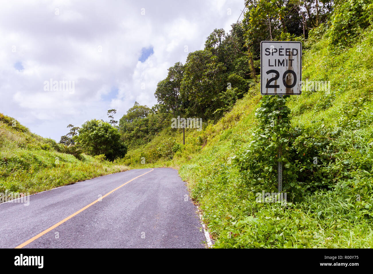 Ee.Uu. blanco de estilo americano del límite de velocidad a 20 km/h en carretera con signo de suciedad lluvia cubierto de manchas de óxido en la selva de la isla de Pohnpei, Micronesia, Oceanía. Foto de stock