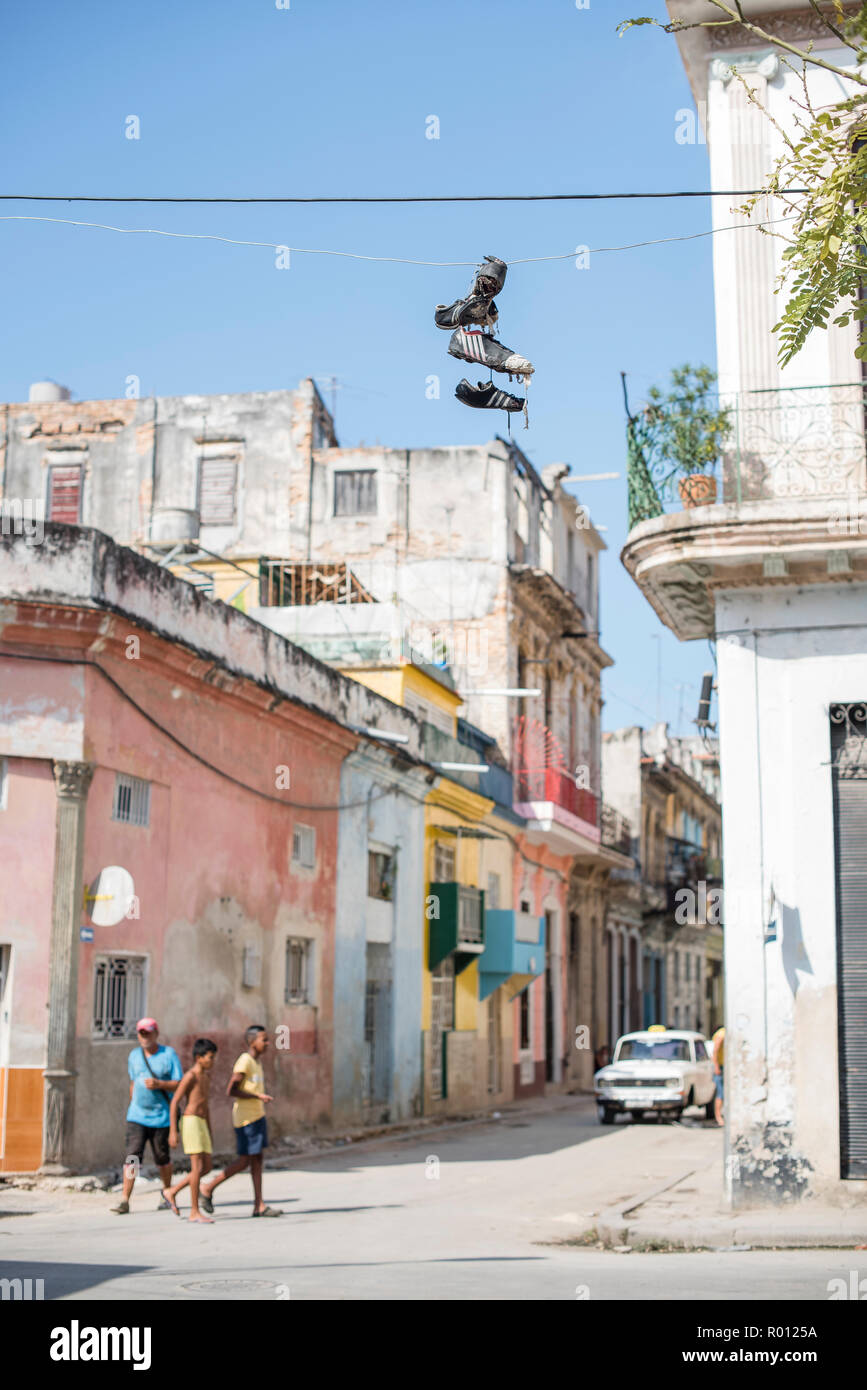 Tres jóvenes amigos caminando por el centro de La Habana. Un par de  zapatillas se cierne sobre un cable encima Fotografía de stock - Alamy
