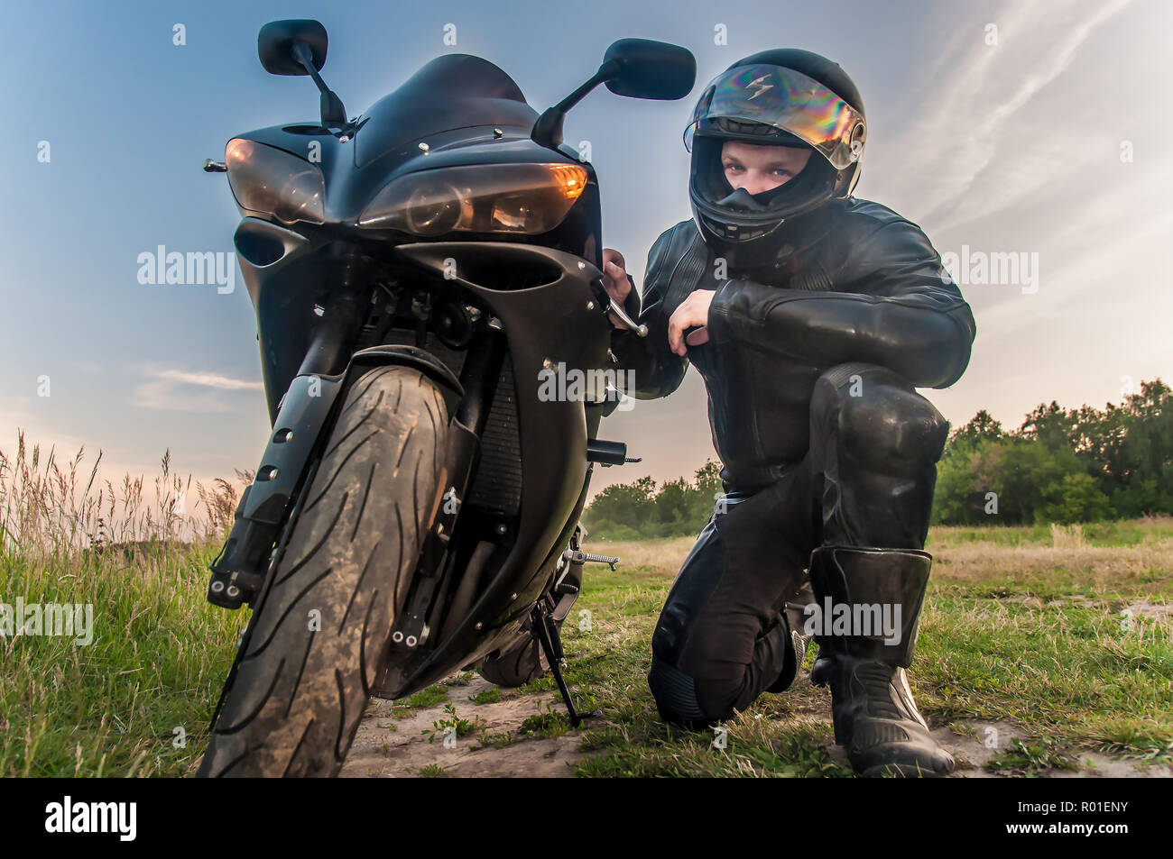 Suite negra biker sentarse cerca de su moto deportiva en un traje protector  negro Fotografía de stock - Alamy