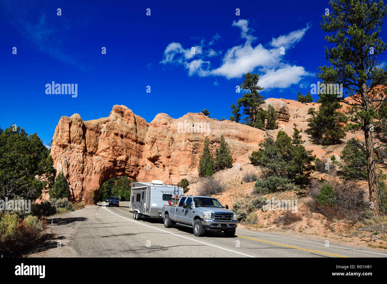 Recogedor con unidades de caravanas a través de una puerta de roca en la Highway 12, Red Canyon, Dixie Bosque, Utah, EE.UU. Foto de stock