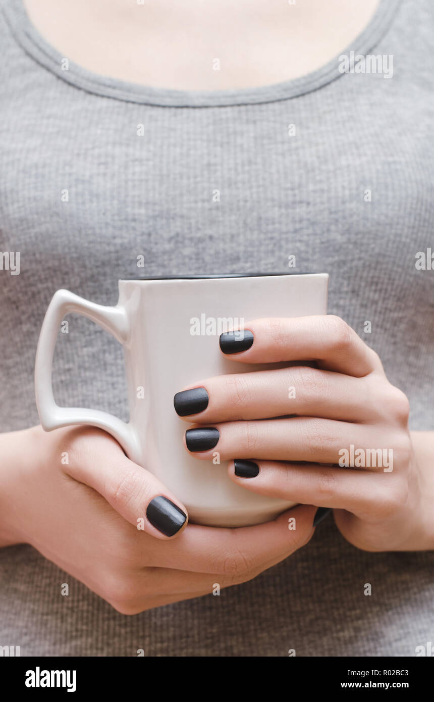 Manos femeninas con negro mate Diseño uñas sujetando la copa blanca  Fotografía de stock - Alamy