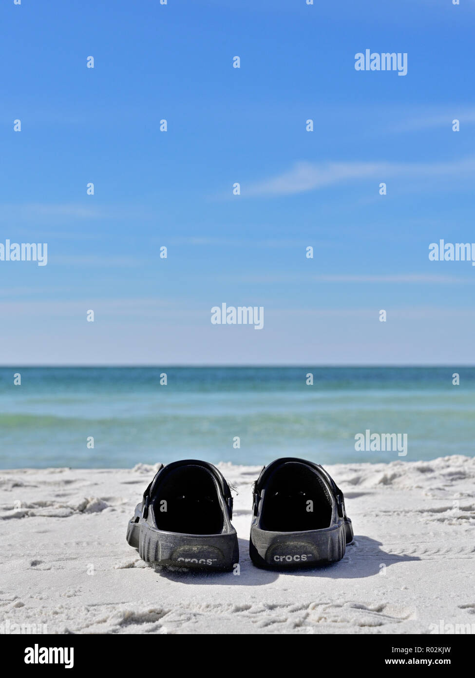 Crocks par de zapatos o sandalias de playa en la costa del golfo de Florida Panhandle blanca arena de playa frente al Golfo de México en Deer Lake State Park, Florida, USA. Foto de stock
