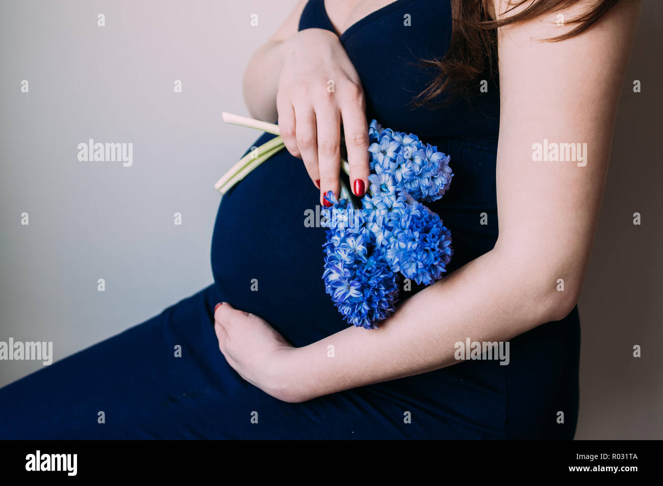 Mujer embarazada en vestido azul oscuro sentado con bouquet de flores  Fotografía de stock - Alamy