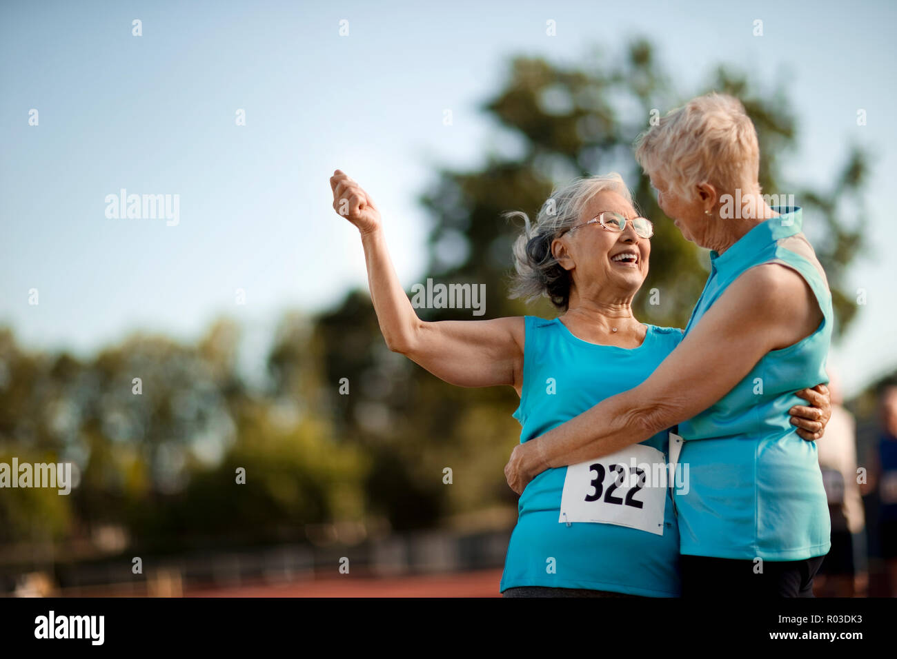 Dos mujeres de edad feliz abrazando después de competir en un evento atlético. Foto de stock