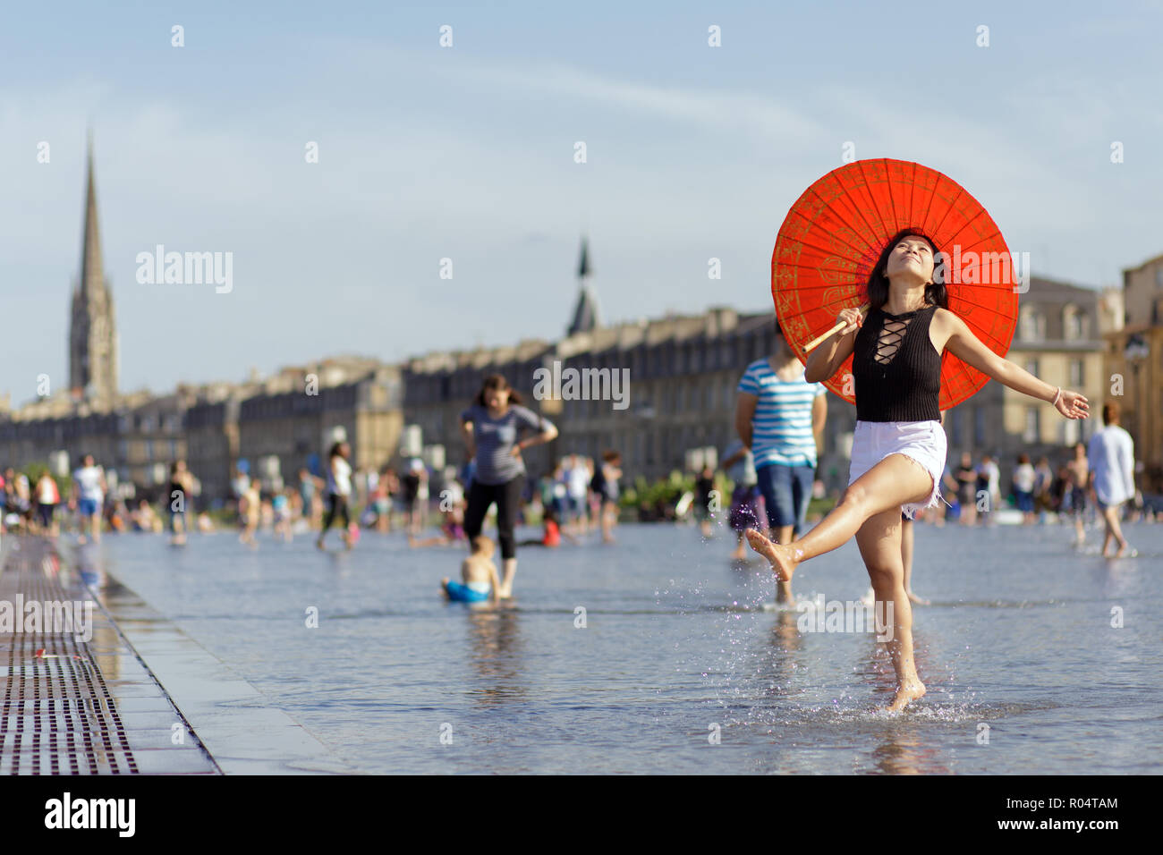 Mujer Asiática sosteniendo un paraguas, baile y salpicando el espejo de  agua en lugar de la bourse en Bordeaux, Francia Fotografía de stock - Alamy