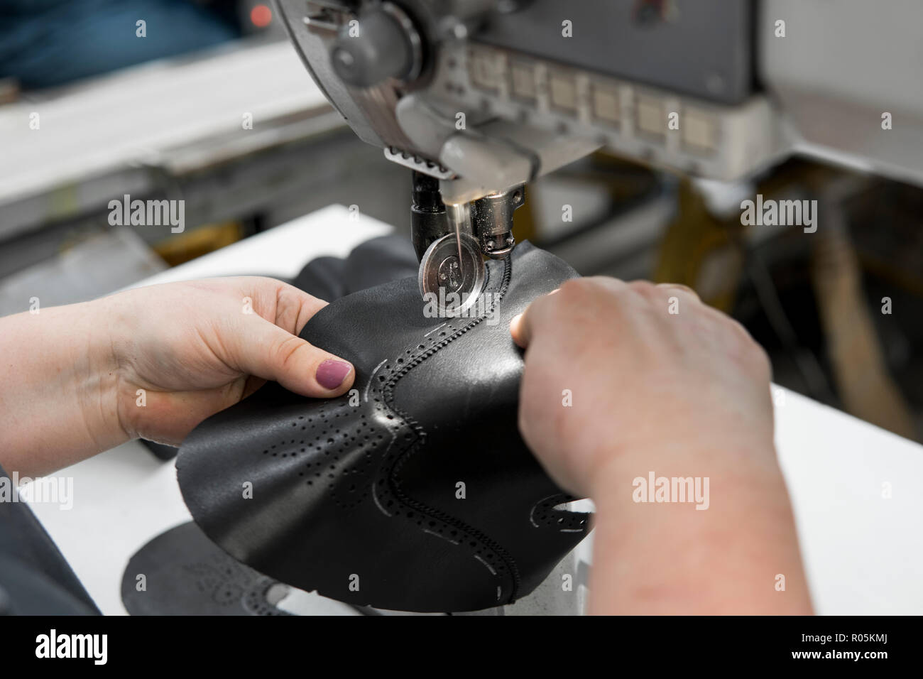 Máquina de coser en un taller de cuero en acción con manos trabajando en  detalles de cuero para calzado. Manos de mujer vieja con la máquina de coser  en la fábrica de