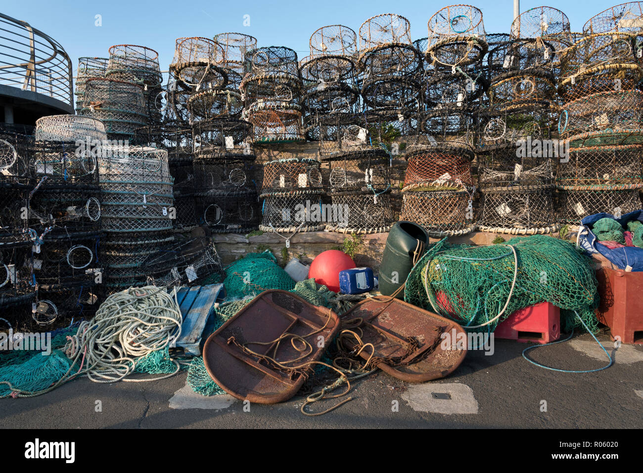 Redes de pesca de langosta, ollas y otros aparejos de pesca en el muelle en el puerto de Brixham, Devon, Reino Unido Foto de stock