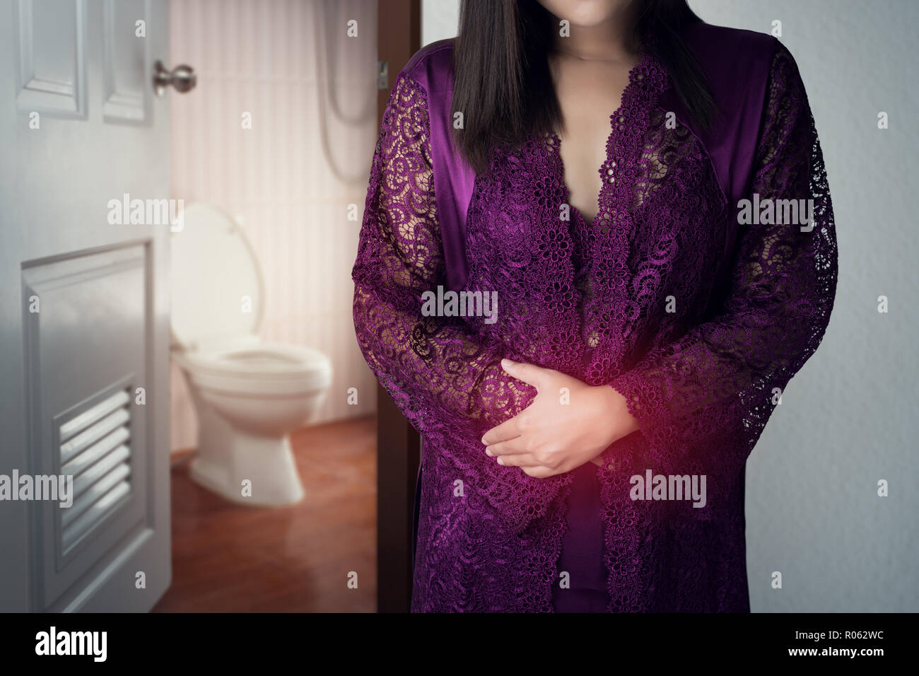 La mujer de túnica de raso púrpura despertarse para ir al baño. Asia, la gente de dolor de estómago dolor de estómago causas de la menstruación. Vidas de stock -