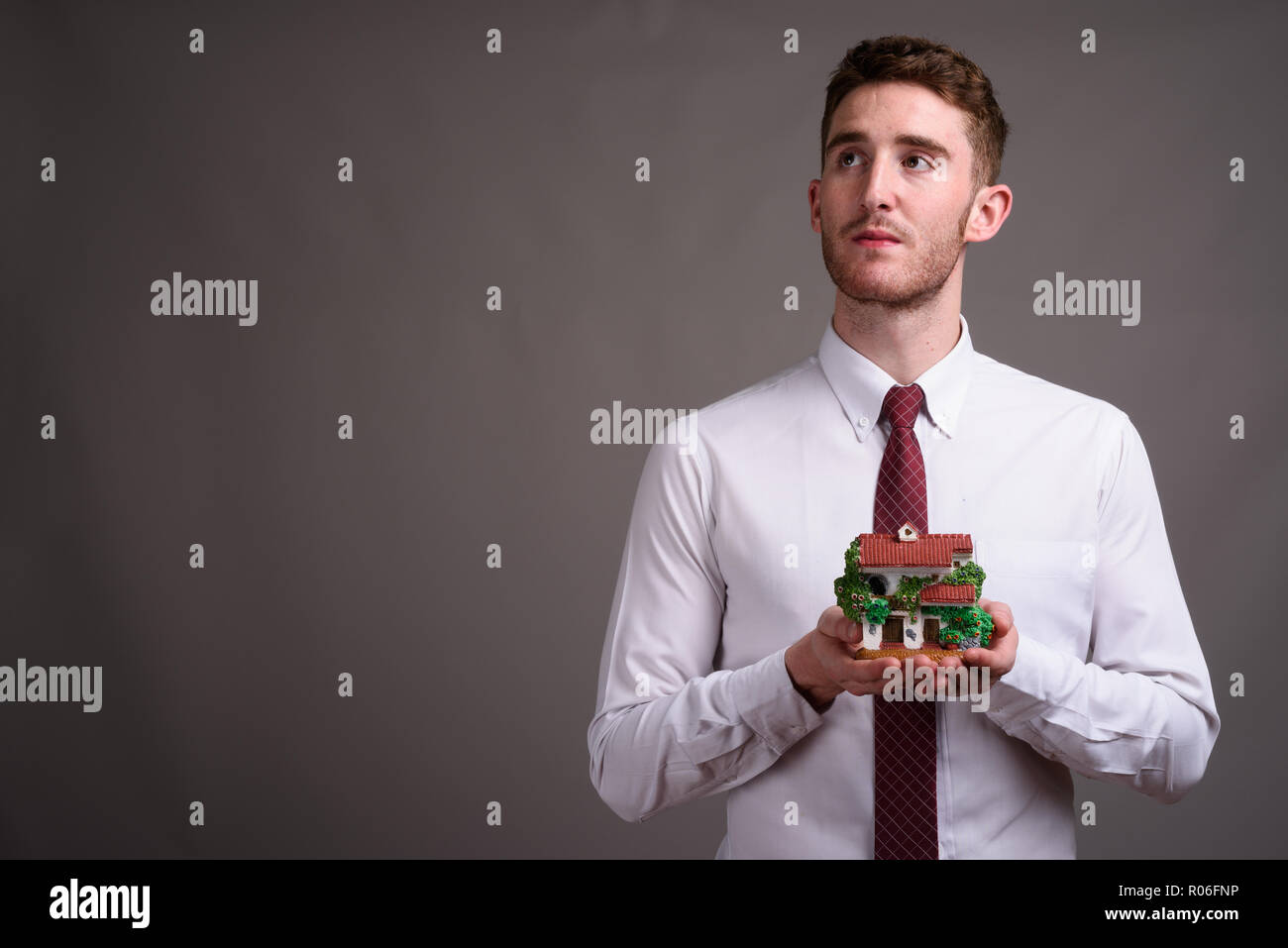 Retrato de joven apuesto empresario contra el fondo gris Foto de stock