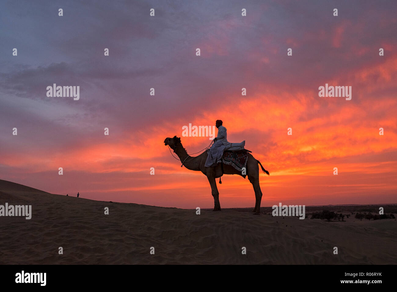 Silhoutte comerciante de camellos atravesando el desierto de Thar en Jaisalmer, India. Foto de stock