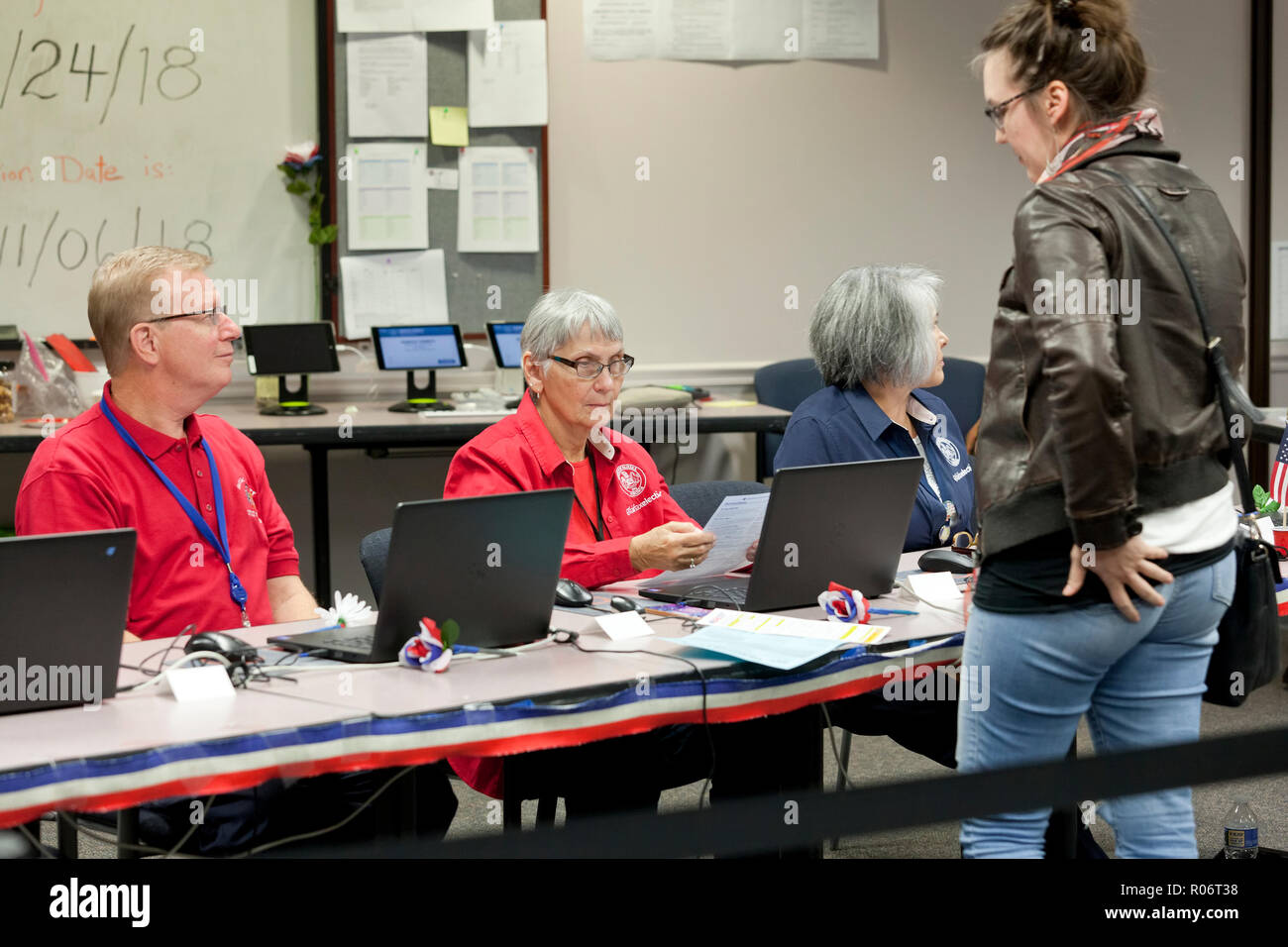 Mujer espera recibir votación intermedia mientras escrutador (funcionario de elecciones) verifica la identidad del votante durante 2018 elecciones midterm - Virginia EE.UU. Foto de stock