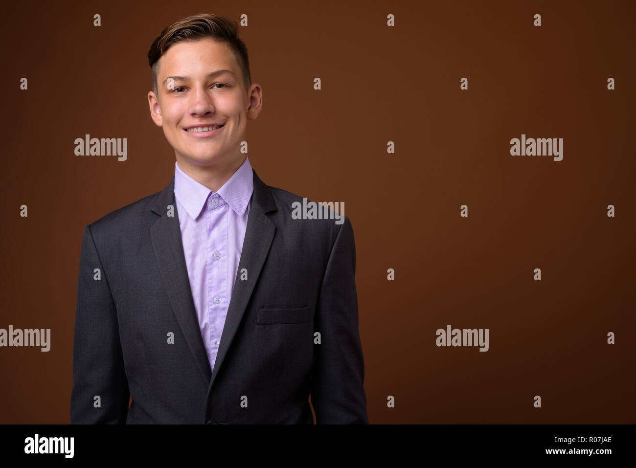 Foto de estudio de joven apuesto empresario contra Brown backgrou Foto de stock