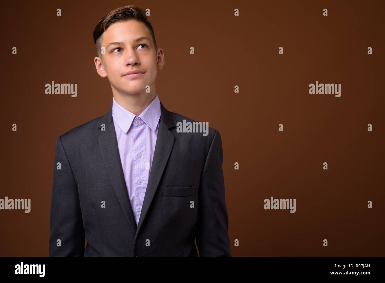 Foto de estudio de joven apuesto empresario contra Brown backgrou Foto de stock