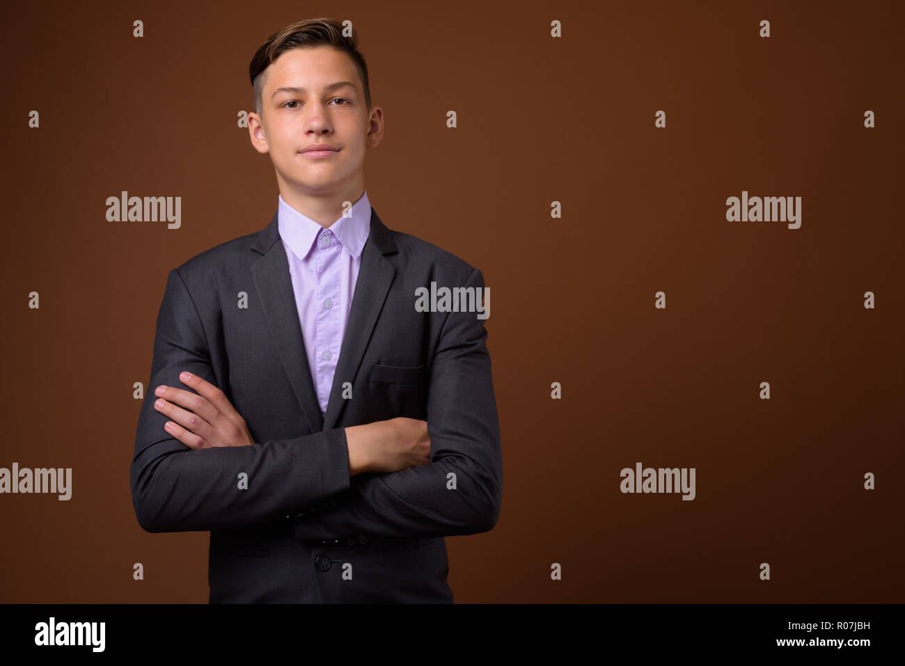 Foto de estudio de joven apuesto empresario contra Brown backgrou Foto de stock