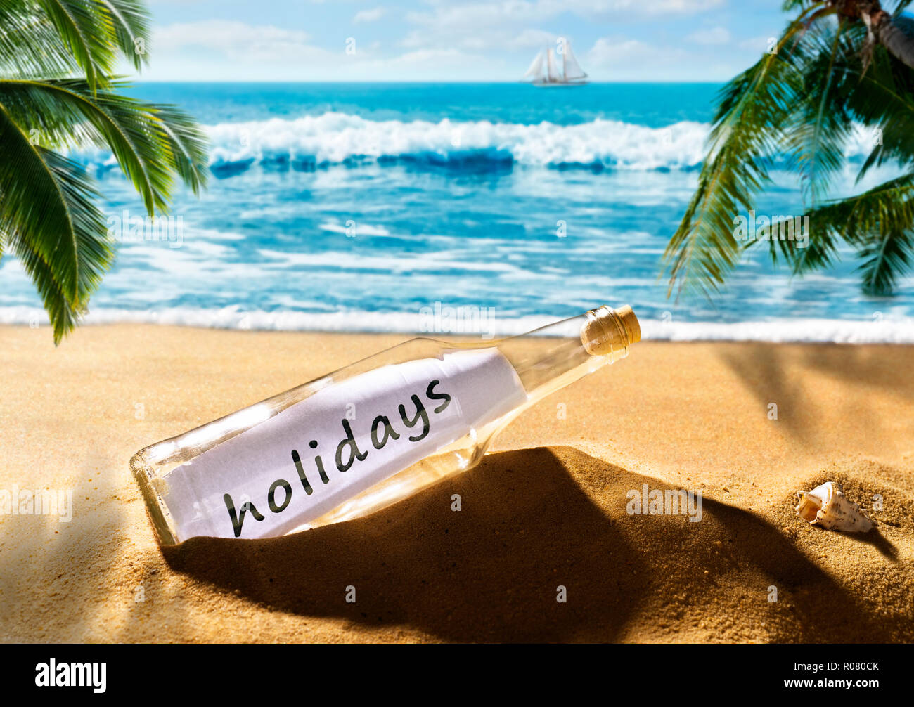 Botella con el mensaje vacaciones en una hermosa playa tropical Foto de stock