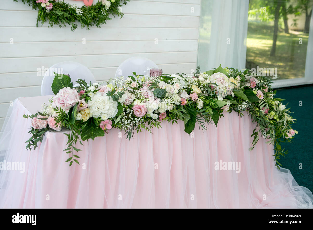 Cena blanca hermosa mesa para recién casados decorado con plantas y tela  larga. Siempre arreglo floral de hortensias, rosas, lirios, gipsophiles un  Fotografía de stock - Alamy