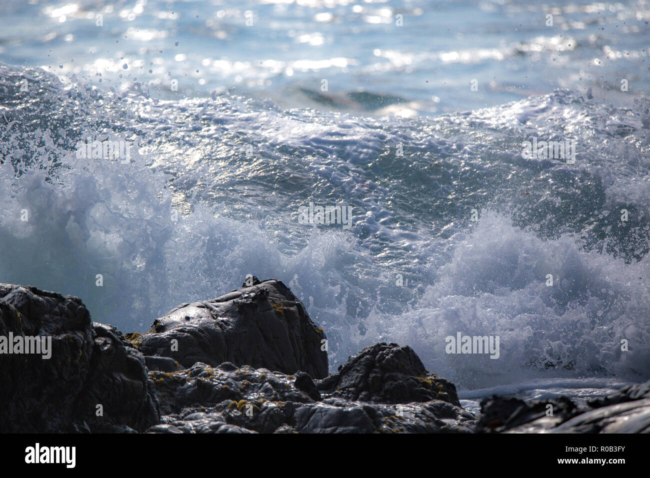 Las olas rompen y rompen en la orilla rocosa Foto de stock