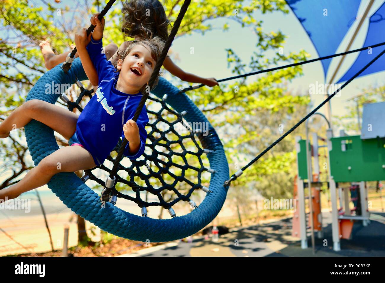Dos niños jugando en un columpio, nido Balgal beach, Queensland, Australia Foto de stock