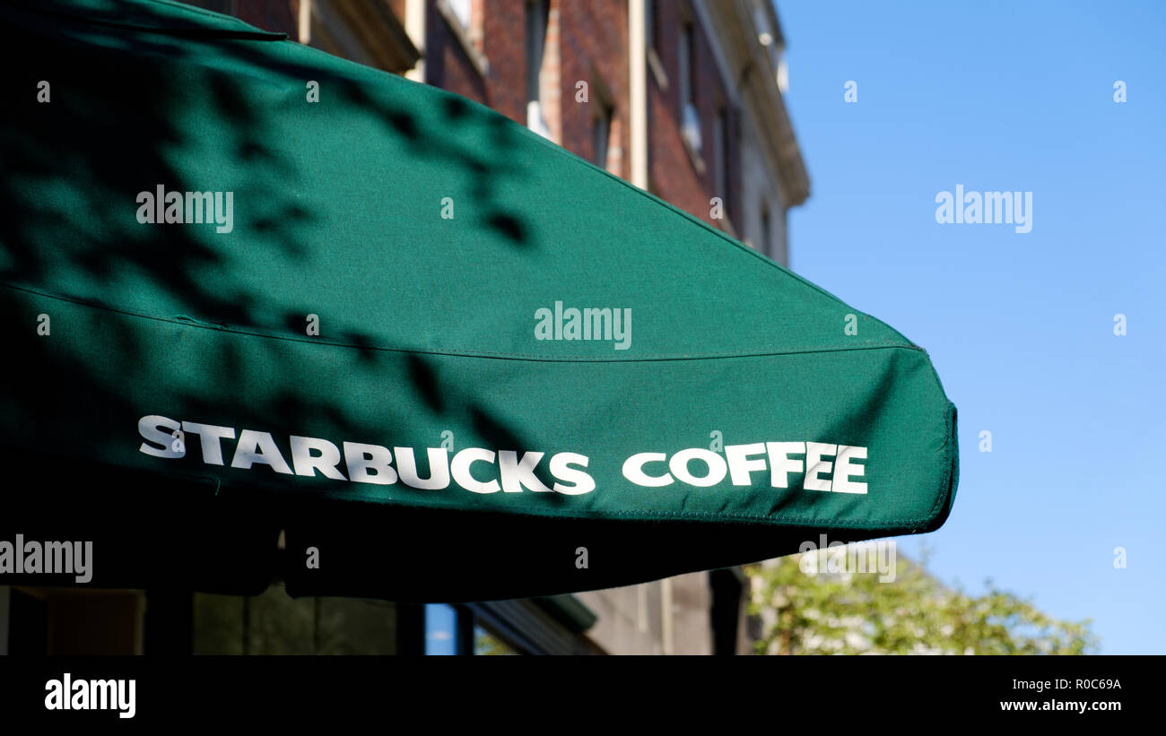 Un Starbucks coffee shop outdoor paraguas Stabucks mostrando claramente el nombre de la marca y colores de marca en un día soleado Foto de stock