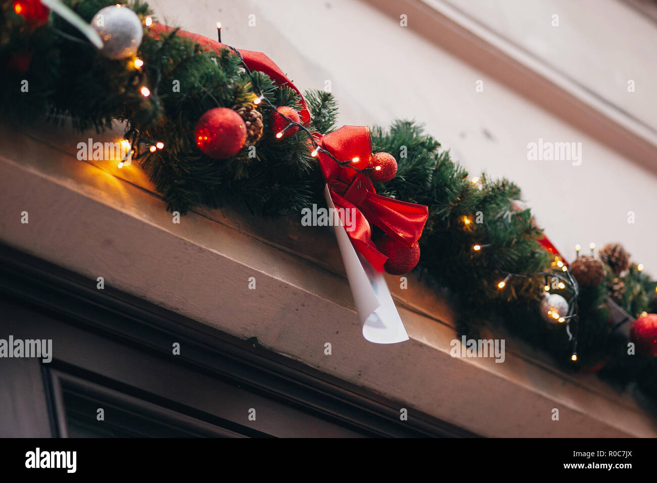 Elegante decoración de navidad, guirnaldas y luces de ramas de abeto con  adornos de color rojo en la ventana en la unión de las calles de la ciudad.  Iluminación y decoración festiva