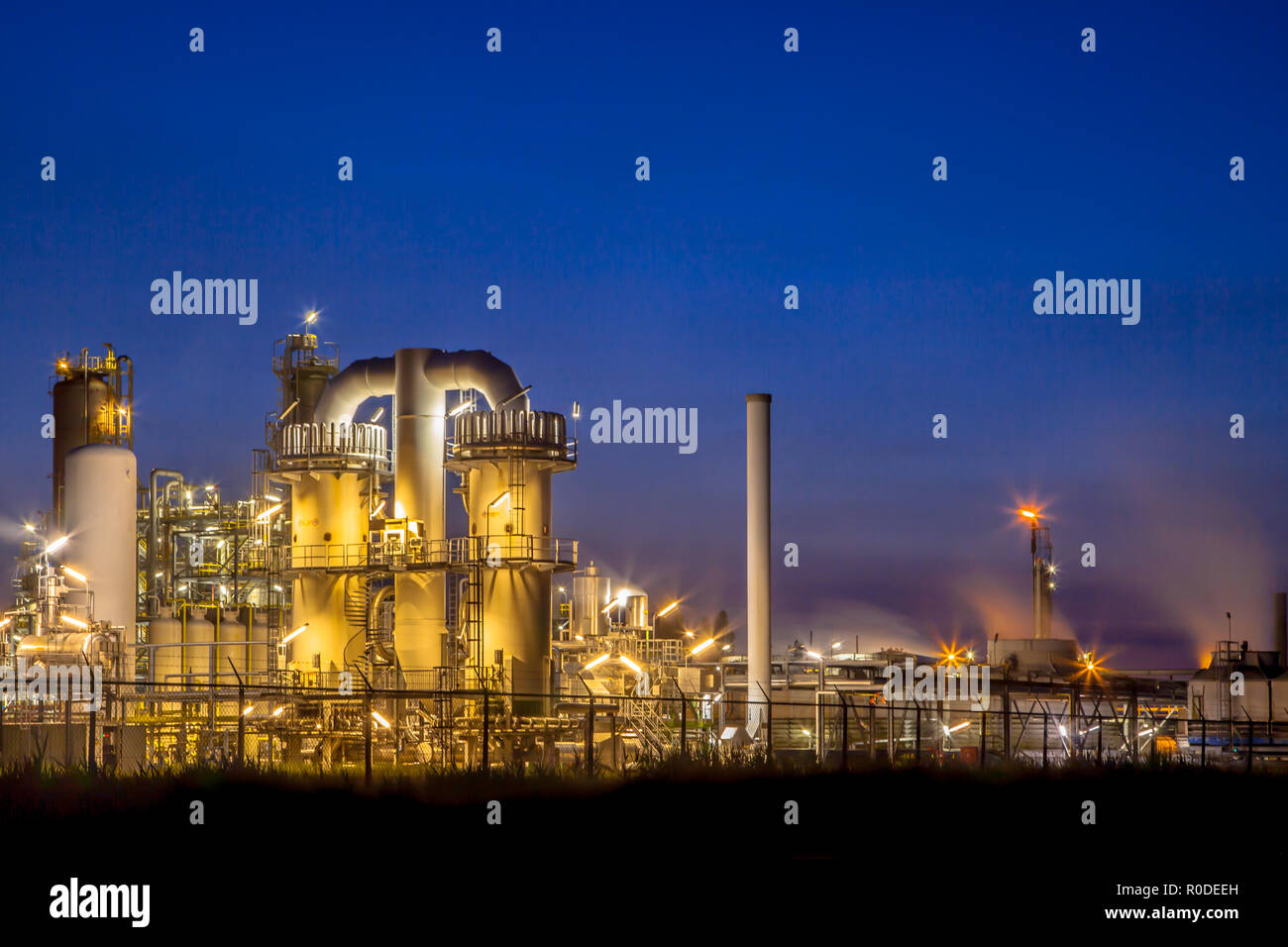 Paisaje de una planta industrial química pesada con mazework de tubos en crepúsculo escenas nocturnas Foto de stock