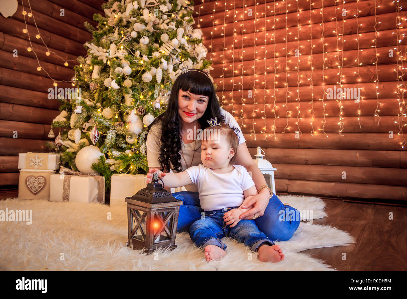 Familia feliz abrir un regalo bajo el árbol en la hermosa ropa. mamá e hija  celebran la Navidad. Madre e hija bajo el árbol de Navidad Fotografía de  stock - Alamy