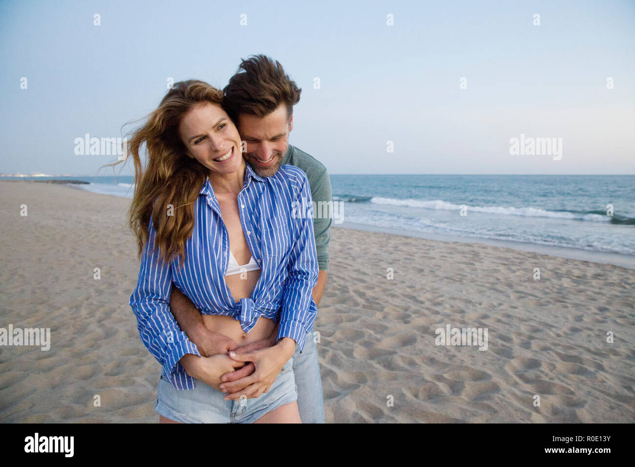El hombre abrazando a la mujer desde atrás en la playa Foto de stock