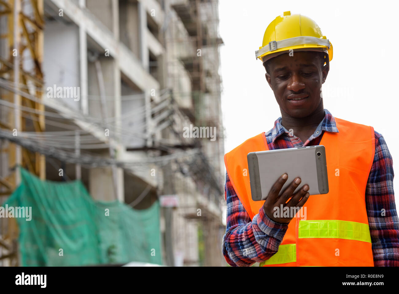 Feliz joven hombre negro africano, trabajador de la construcción sonriente mientras Foto de stock