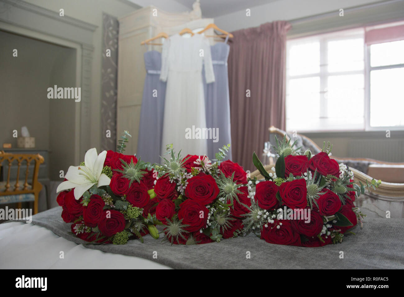 Ramos de novia de rosas rojas y vestidos de novia de colgar al fondo, en un  día de boda novias Fotografía de stock - Alamy