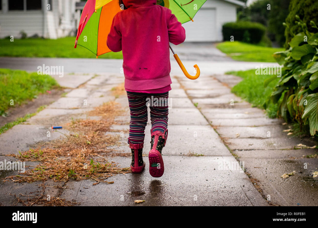 Una de 4 años camina en la lluvia sosteniendo un paraguas y llevaba botas agua Fotografía de stock - Alamy