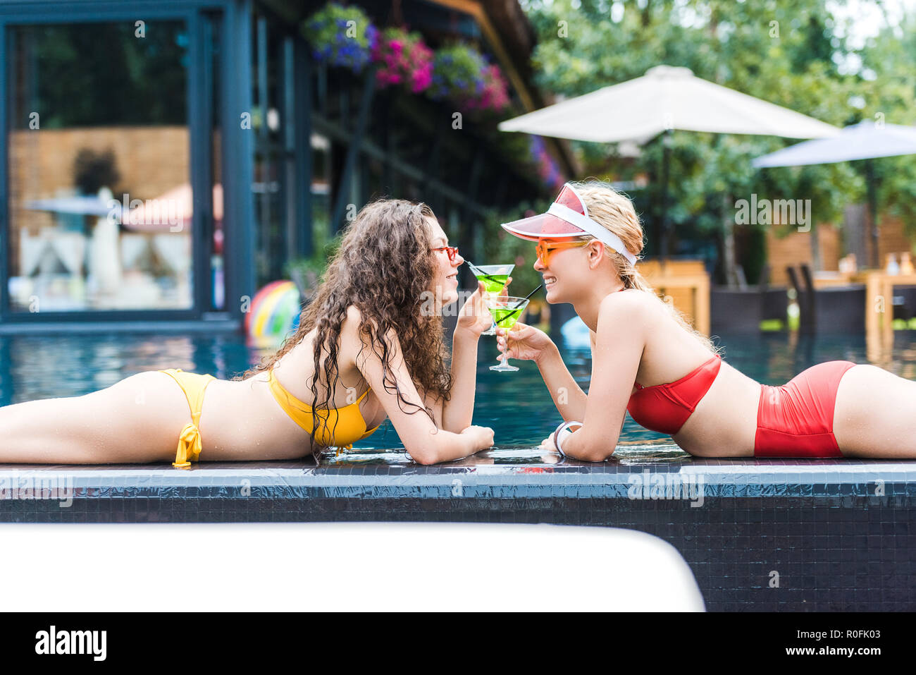 Feliz atractivo femenino amigos de beber cócteles en la piscina. Foto de stock