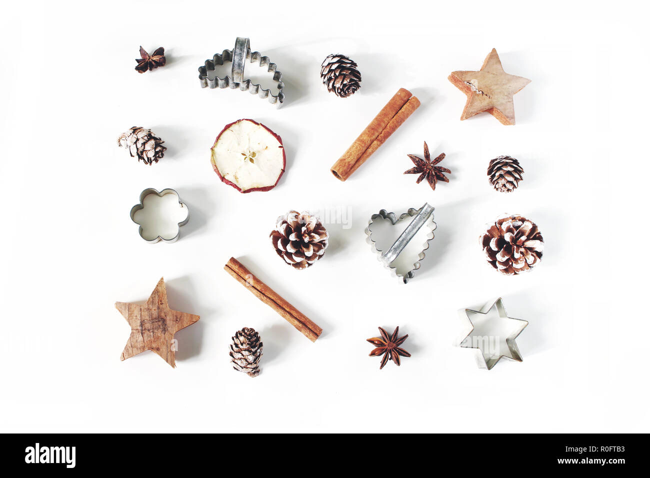 Navidad estilo festivo, el patrón de composición de alimentos. Piñas, manzanas secas, canela, vintage cortadores para galletas y anís estrellas aislado sobre fondo blanco de madera. Sentar planas, vista superior. La cocción. Foto de stock