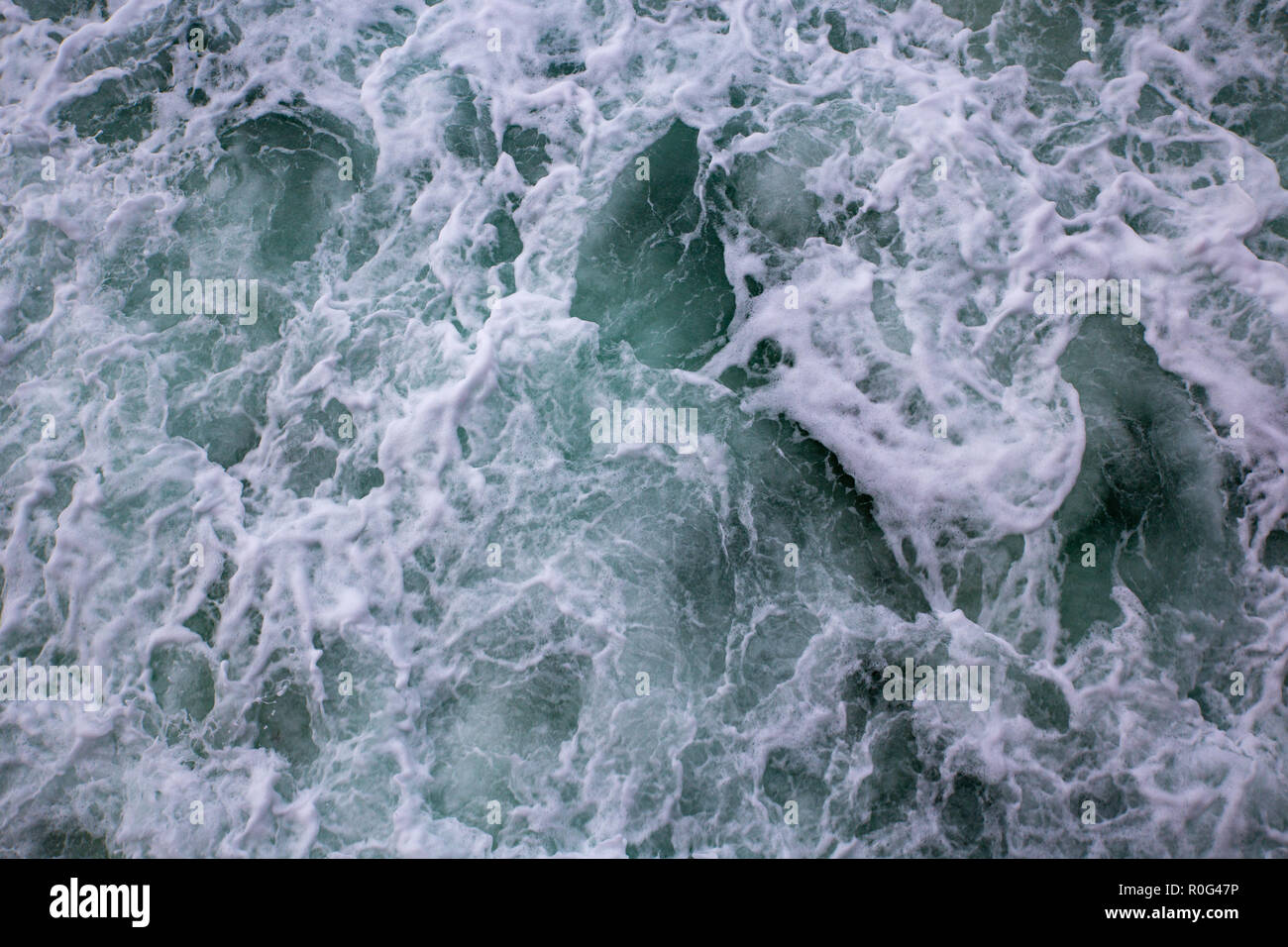 Las olas que rompen en la orilla crear espumosa blanca batiendo el agua Foto de stock