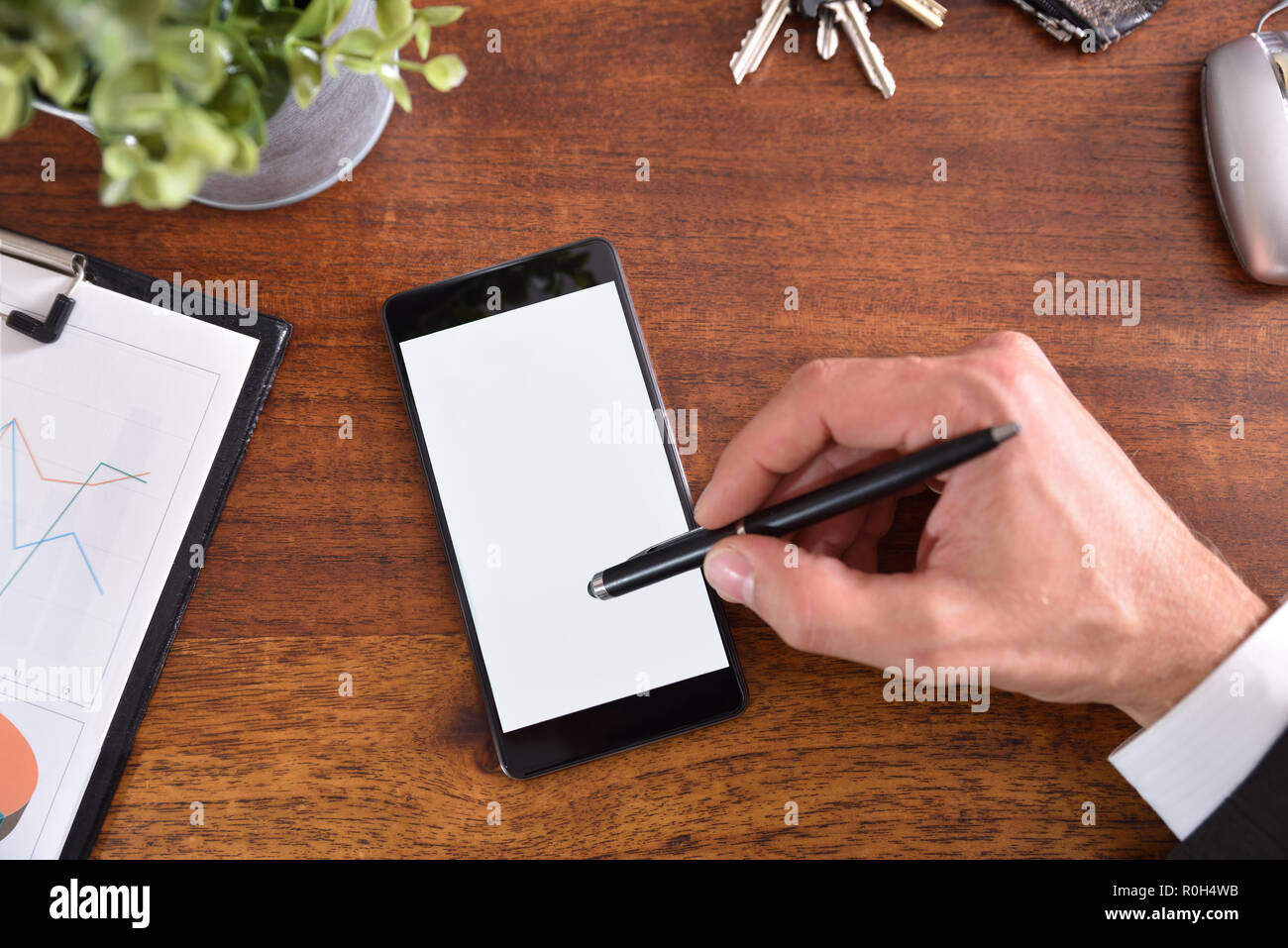 Escritorio de negocios interactuando con la mano en un teléfono móvil con el lápiz táctil capacitiva activa. Composición horizontal. Vista superior Foto de stock