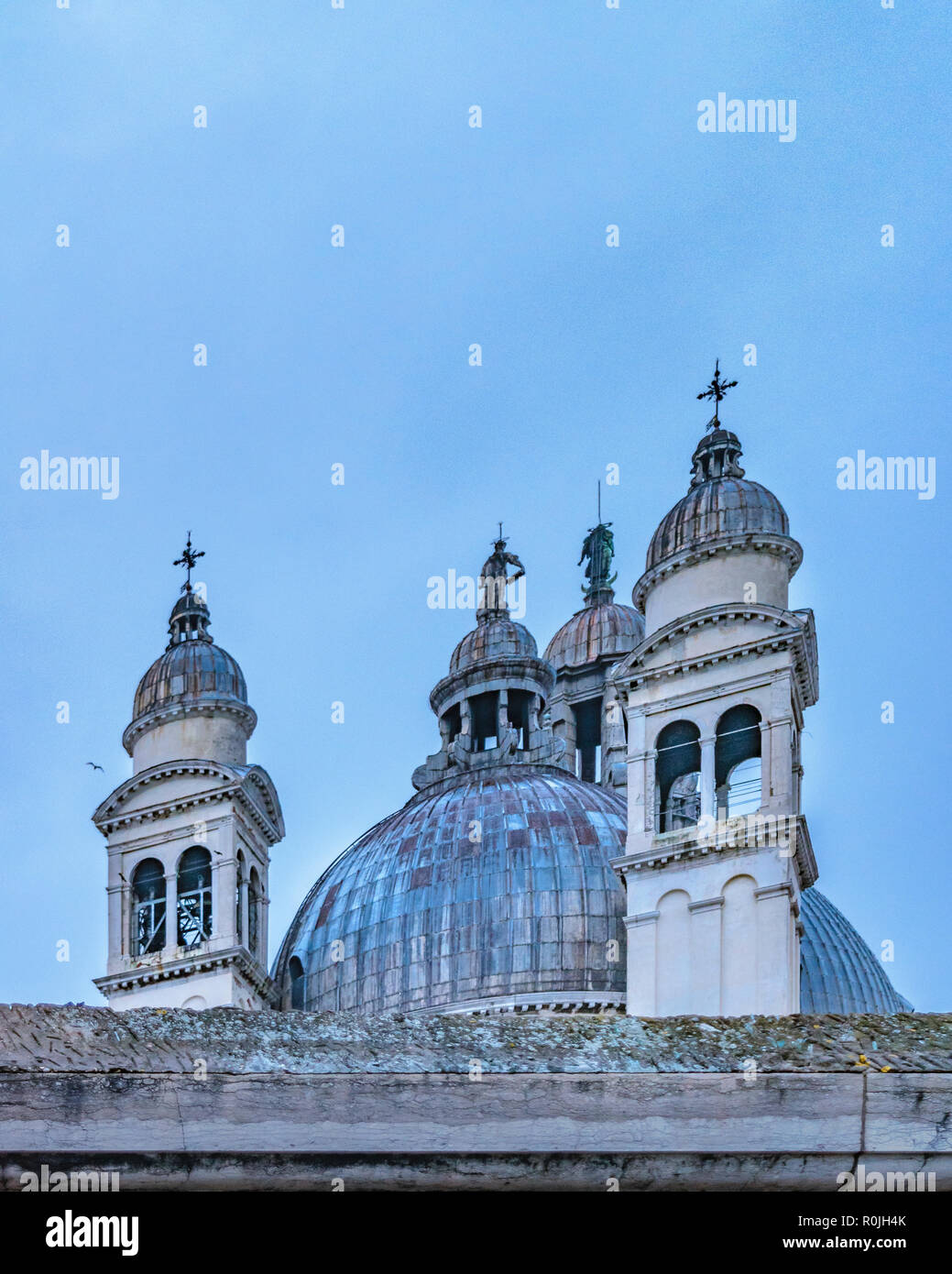 Ángulo de visión baja exterior de antiguos campanarios de estilo barroco y la iglesia de la cúpula en el centro histórico de Venecia, Italia Foto de stock