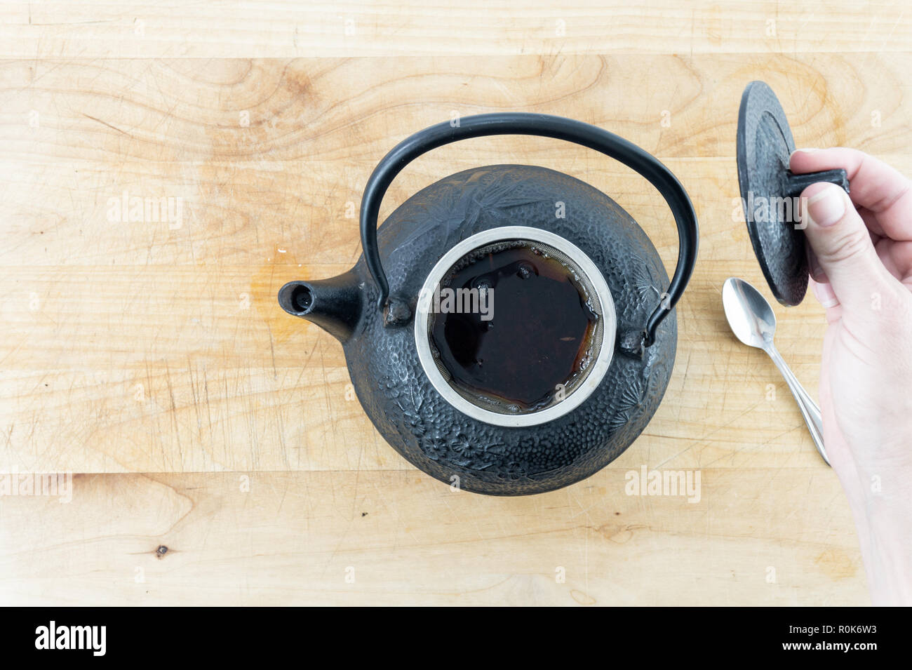 Mujer en un café vierte té de una tetera de hierro fundido negro