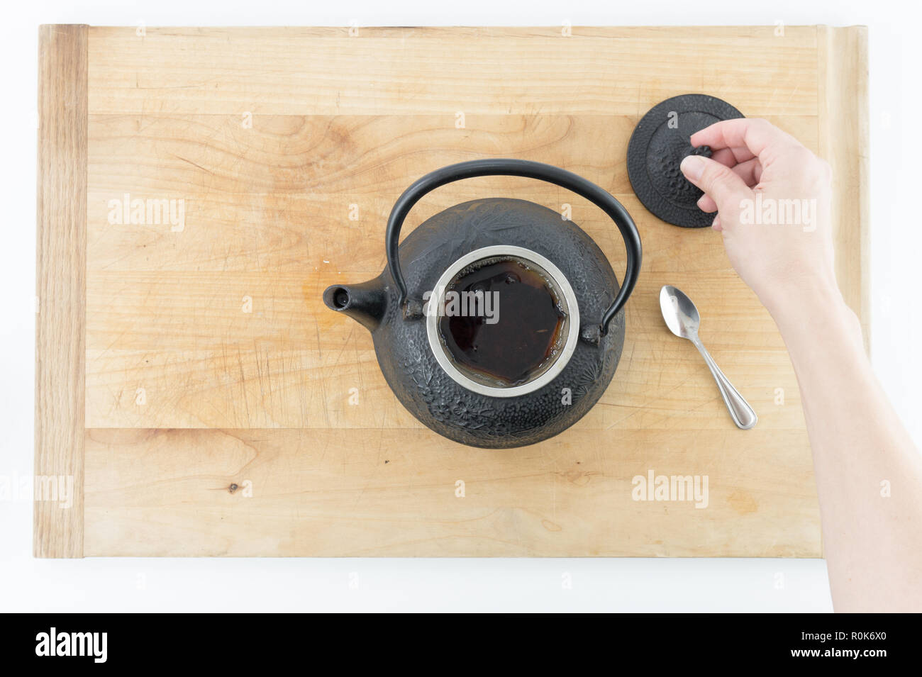 Mujer en un café vierte té de una tetera de hierro fundido negro