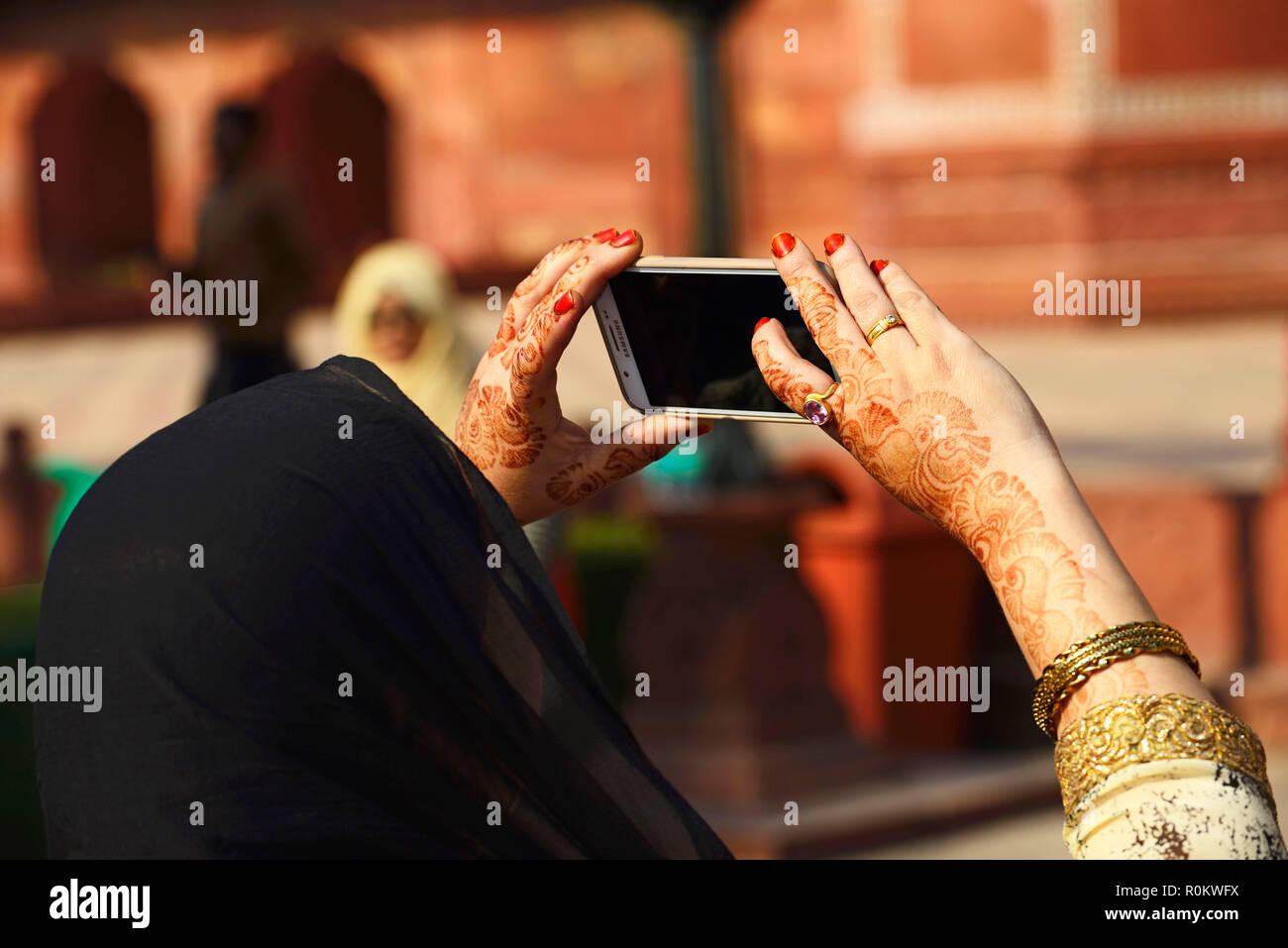 Mujer musulmana con manos decoradas con henna fotografiar con el smartphone, Uttar Pradesh, India Foto de stock