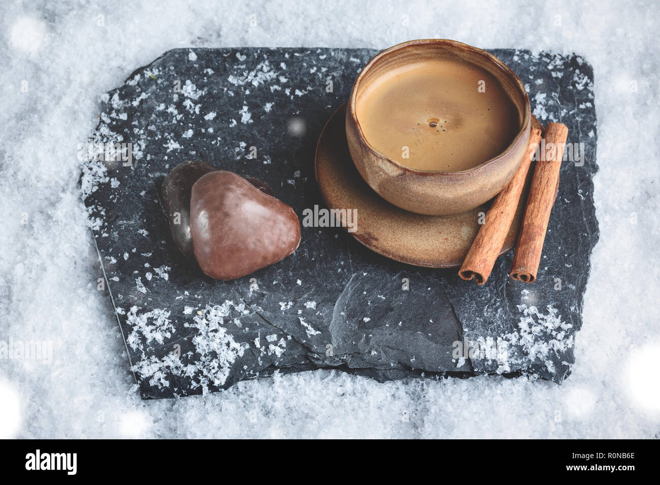 Taza de café con forma de corazón y decoración de invierno sobre la nieve de jengibre Foto de stock