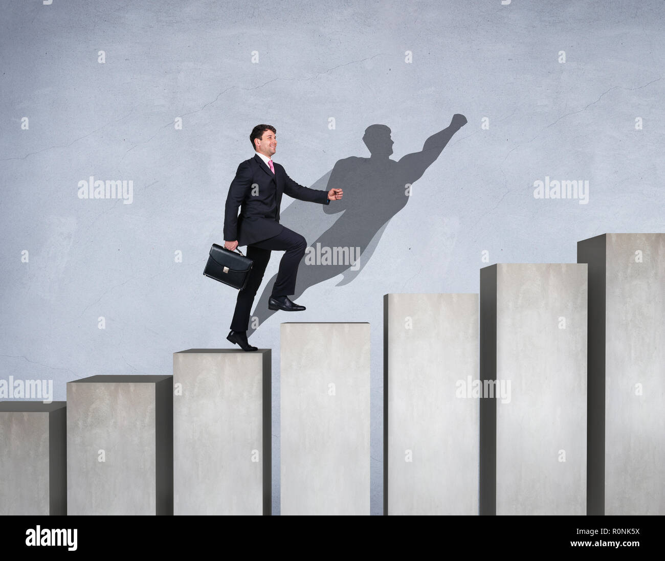 Empresario subir en el escalafón de la carrera con los superhéroes sombra en la pared. Foto de stock
