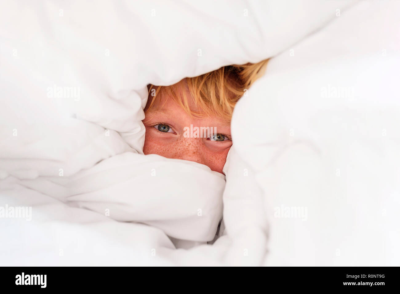 Retrato de un niño escondido en un edredón Foto de stock