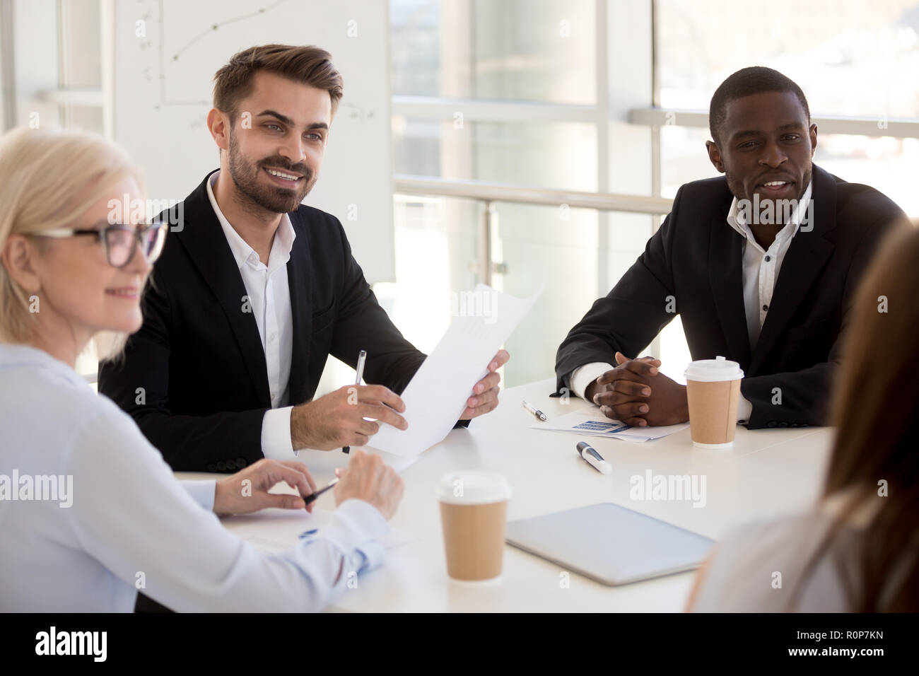 Interesados diversos empleados escuchan hablar a un colega Foto de stock