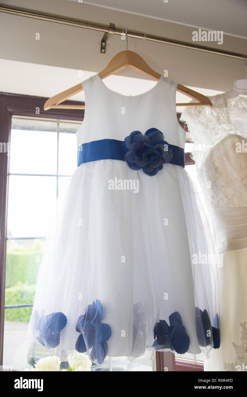 Las damas de honor vestido de colgar a la espera de ser usado en un día de  boda con cinturón azul y flores de color azul sobre un vestido blanco  Fotografía de