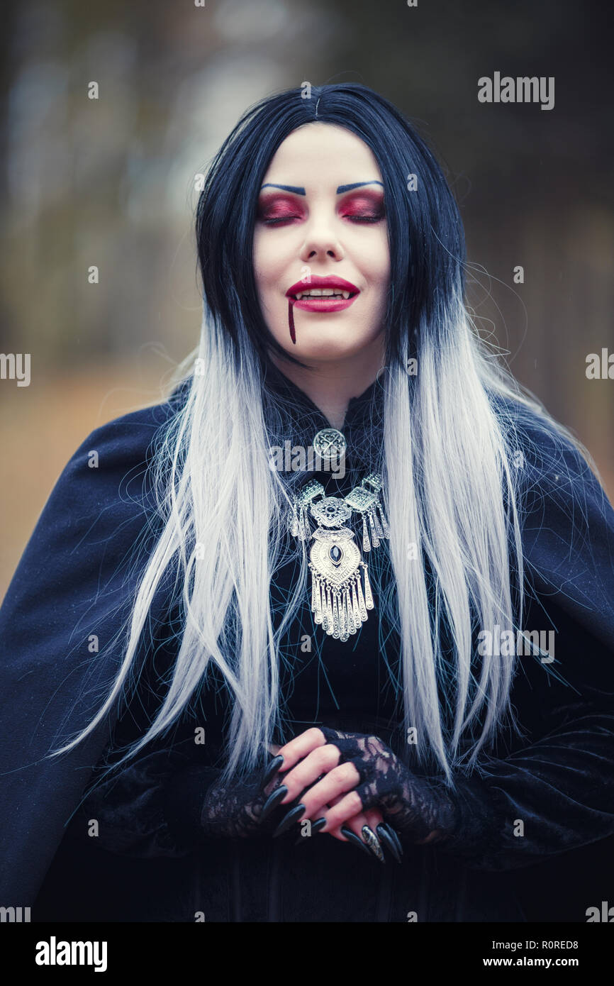 Foto de vampiresa gótica con los ojos cerrados con sangre en la Boca en  fondo borroso Fotografía de stock - Alamy