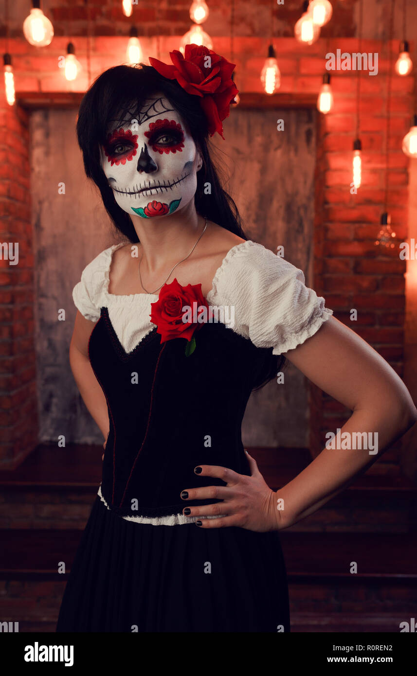 Foto de chica halloween con maquillaje blanco en su cara, cosido en su  boca, ojos negros en el sombrío telón de fondo de la pared de ladrillo con  la quema de luces