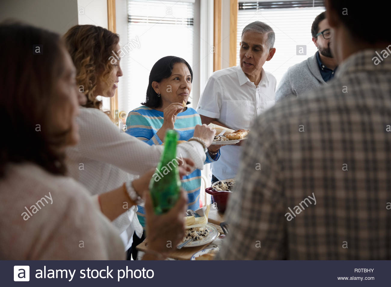 Familia Latinx disfrutando cena buffet en la cocina Foto de stock
