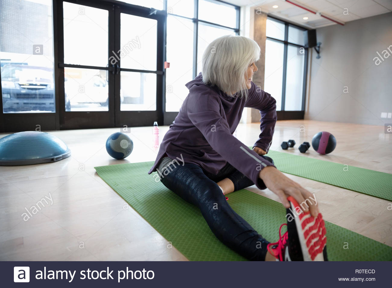 Mujer mayor estiramiento de la pierna en el gimnasio studio Foto de stock