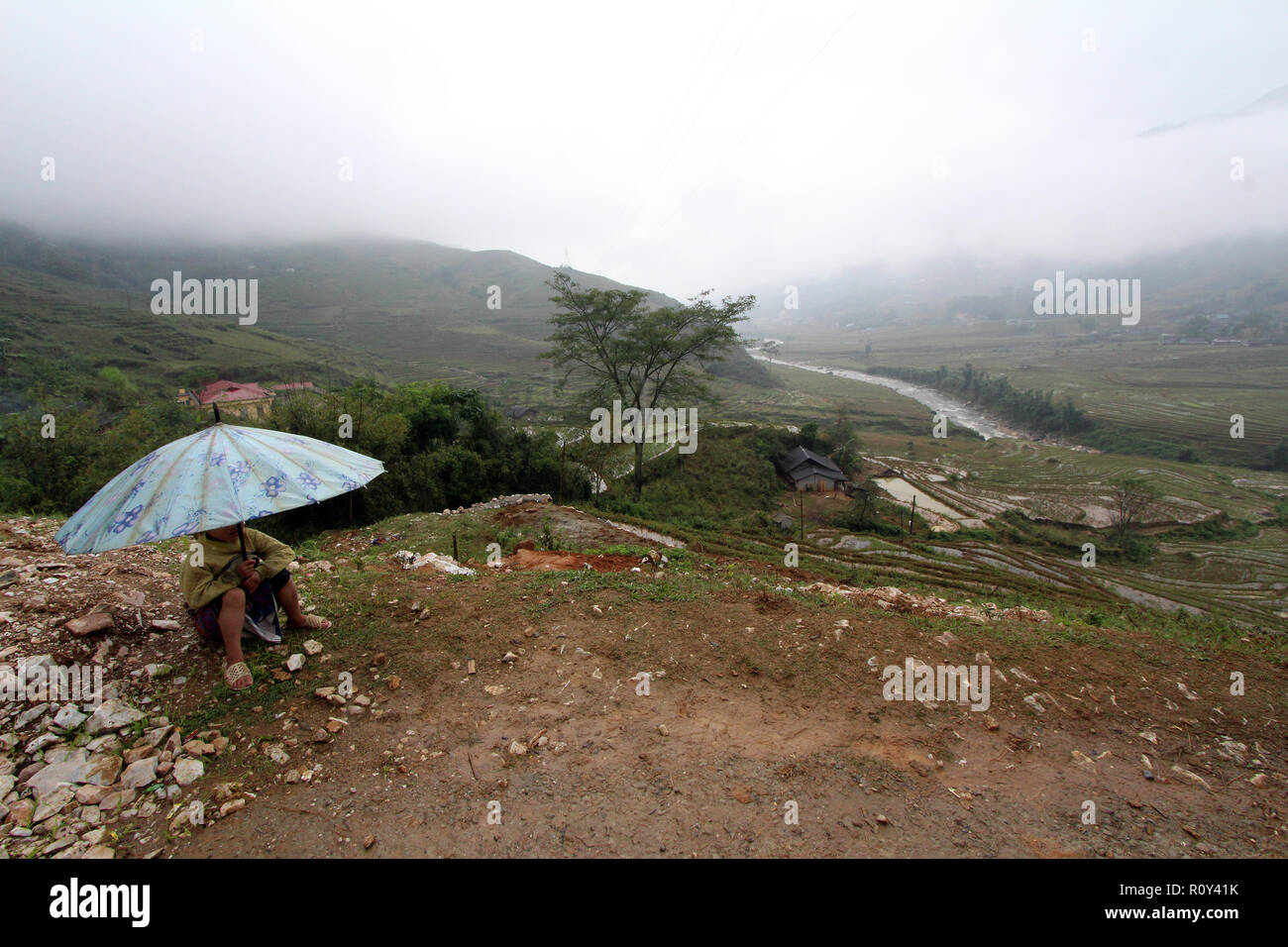 Niño descanse bajo una sombrilla en una colina fuera de pueblo de Sapa, VietnamBB Foto de stock