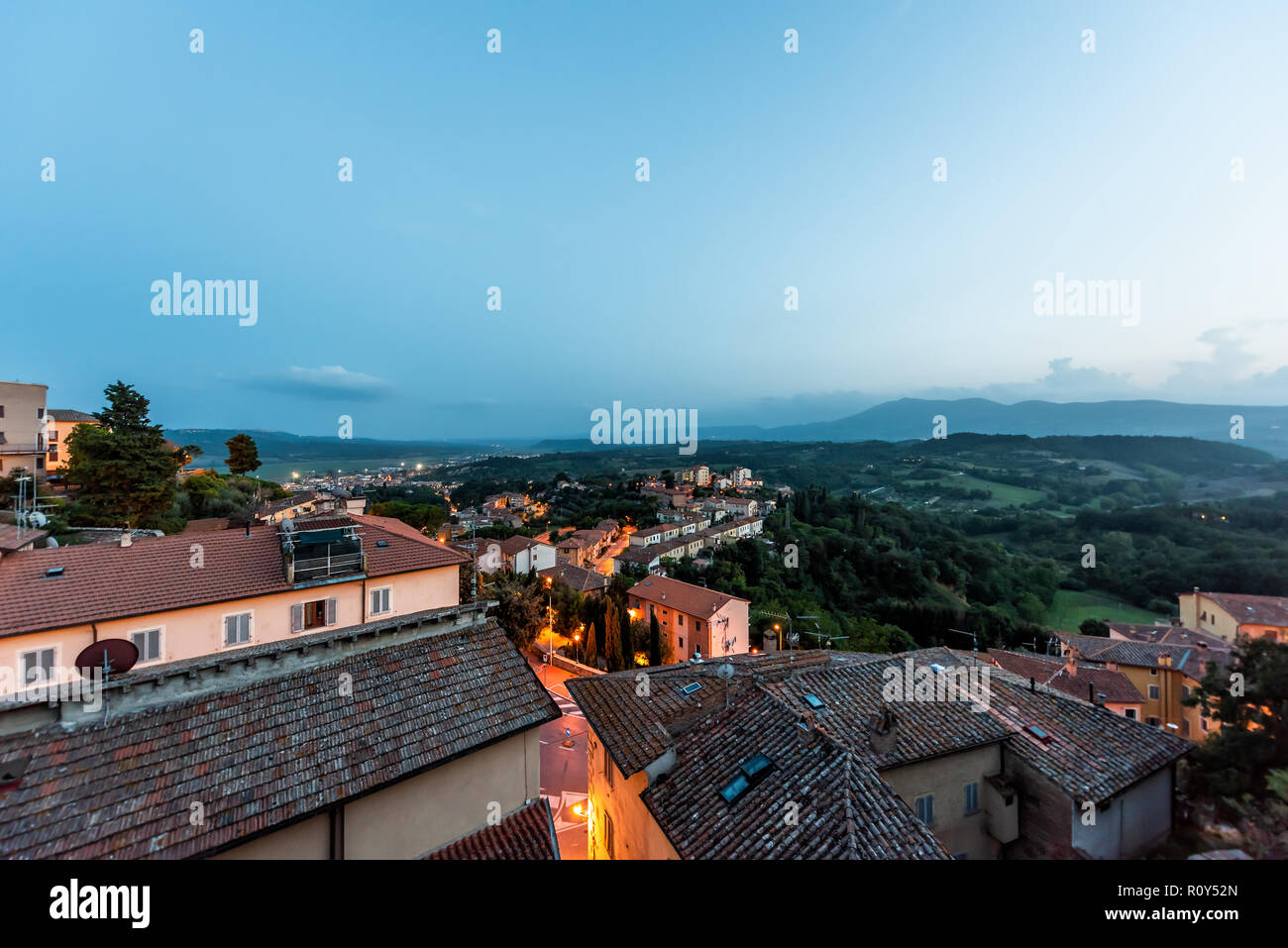 En Chiusi niebla niebla de noche, tarde o mañana en Umbría, Italia, cerca de Toscana, iluminado con luces en las calles, casas de la azotea en la montaña campo, r Foto de stock